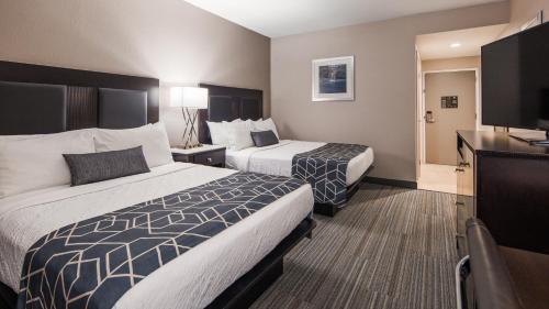a hotel room with two beds and a flat screen tv at Best Western Plus Wilkes Barre-Scranton Airport Hotel in Pittston