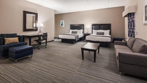 a hotel room with two beds and a couch at Best Western Plus Wilkes Barre-Scranton Airport Hotel in Pittston