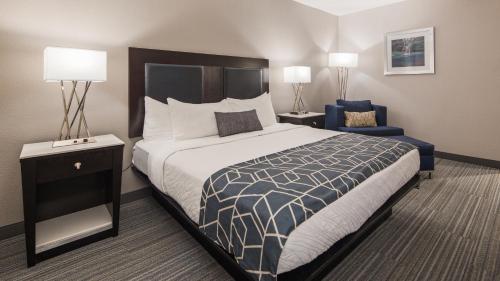 a bedroom with a large bed and a blue chair at Best Western Plus Wilkes Barre-Scranton Airport Hotel in Pittston