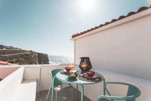a table with two chairs and two candles on a balcony at Azenhas do Mar West Coast Design and Surf Villas in Sintra
