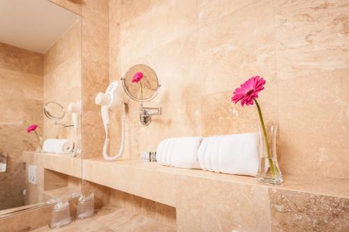 baño con lavabo y jarrón con flor en Grand Hotel Coroana, en Bistriţa