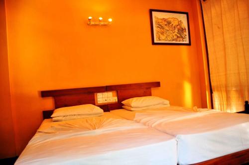 two beds in a bedroom with an orange wall at Heritage Belihuloya Resort in Belihul Oya