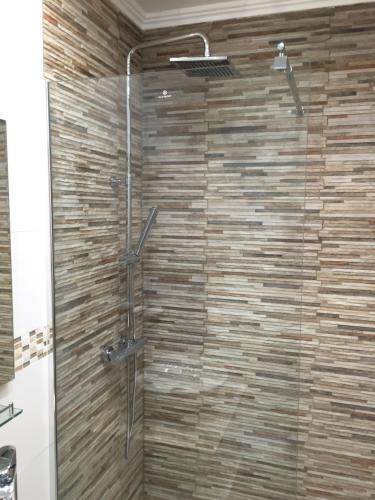 a shower in a bathroom with a wooden wall at Fairway View Penthouse in Murcia