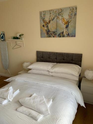 a bed with white sheets and two deer paintings on the wall at Smeaton serviced Accommodation in Liverpool
