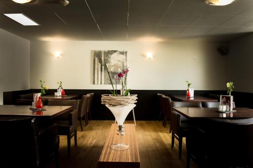 een eetkamer met tafels en een vaas met bloemen erin bij Hotel Restaurant Les Jumeaux in Gulpen