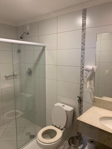 a bathroom with a toilet and a glass shower at Barretos Park Hotel - Condo Hotel in Barretos