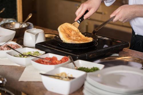 a person cooking food in a pan on a grill at Hotel Linderhof in Erfurt