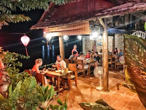 un grupo de personas sentadas en mesas en un restaurante en Phong Nha Coco House, en Phong Nha