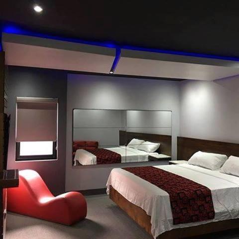 a hotel room with two beds and a red chair at Motel Boutique Xpress in Ensenada