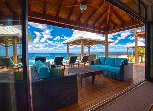 a porch with blue chairs and tables and the ocean at Vivaro Roatan South House in West End