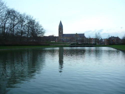 a view of a lake with a church in the background at Hotel Restaurant Les Jumeaux in Gulpen
