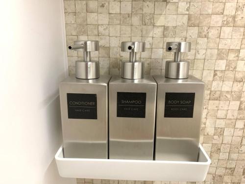 two silver soap dispensers on a wall in a bathroom at ペンション マカナレアリゾート沖縄 in Ginowan