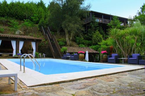 a swimming pool with blue chairs and a house at Casas Da Azenha in Vila Nova de Cerveira