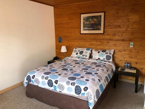 Un dormitorio con una cama con una pared de madera. en Alpine motel, en Rocky Mountain House