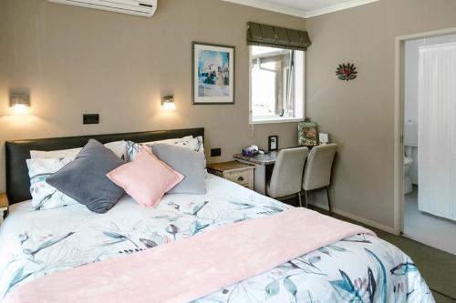 a bedroom with a bed with pillows and a desk at The Nunnery in Te Aroha