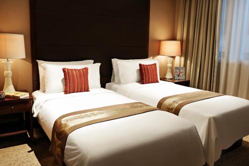a hotel room with two beds and two lamps at Oakwood Premier Cozmo Jakarta in Jakarta