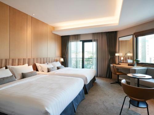 um quarto de hotel com duas camas e uma secretária em The Suites Hotel Jeju em Seogwipo