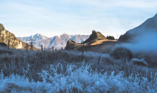 a field of grass with mountains in the background at Gibbston Valley Lodge and Spa in Queenstown