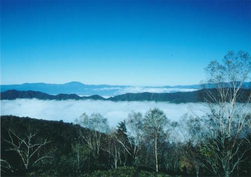 a view of a foggy valley with trees and mountains at Shirabiso Kogen Amanogawa in Iida
