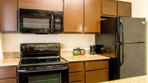 a kitchen with a stove and a microwave and a refrigerator at Studio 6-San Antonio, TX - Lackland AFB in San Antonio