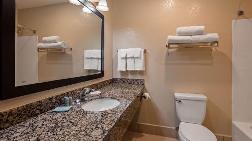 a bathroom with a sink and a toilet and a mirror at Best Western Apache Junction Inn in Apache Junction