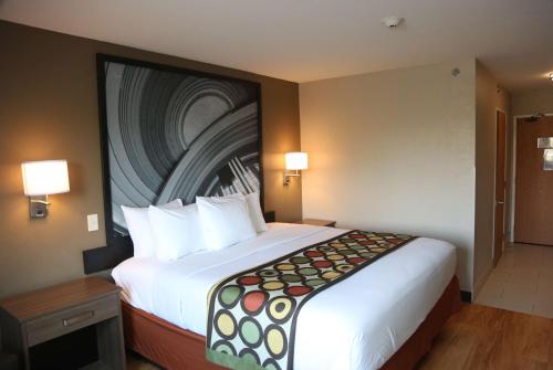 a hotel room with a large bed with a painting on the wall at Super 8 by Wyndham Portsmouth in Portsmouth