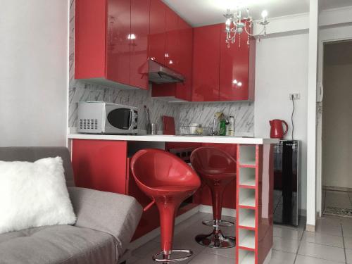 a small kitchen with red cabinets and a red stool at Depto Metro Cal y Canto in Santiago