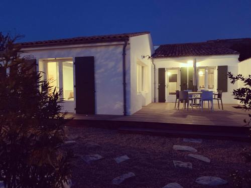 ein Haus mit einer Holzterrasse in der Nacht in der Unterkunft La Maison de l’Ocean - plage à 75 mètres in Saint-Martin-de-Ré