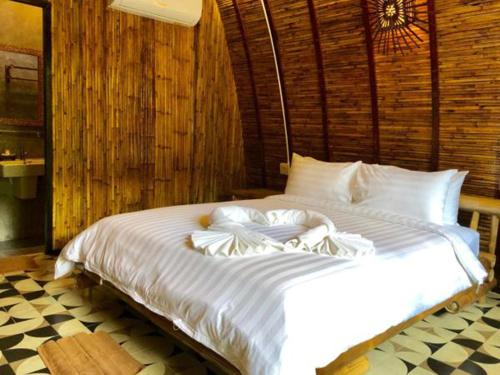 a large white bed in a room with wooden walls at Cicada Lanta in Ko Lanta