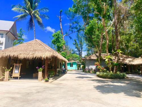 a building with a straw roof and a palm tree at Cicada Lanta in Ko Lanta