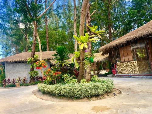a house with a tree and flowers in front of it at Cicada Lanta in Ko Lanta