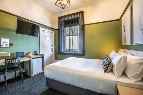 Port Adelaide的住宿－Nightcap at Exeter Hotel，配有一张床和一张书桌的酒店客房