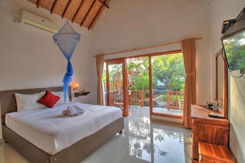 a bedroom with a bed and a television and a balcony at Saren Villa in Nusa Penida