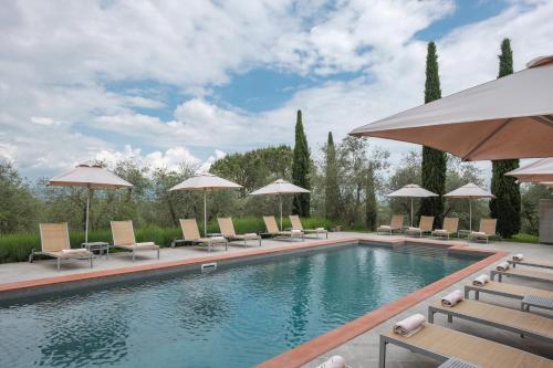 uma piscina com cadeiras e guarda-sóis em Fontelunga Hotel & Villas em Pozzo