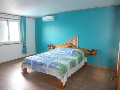 ein Schlafzimmer mit einem Bett in einer blauen Wand in der Unterkunft La Pointe au Corail in Sainte-Rose