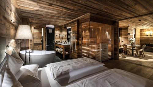 a bedroom with a tub and a bed and a bathroom at Chalet Cogolara in Colfosco