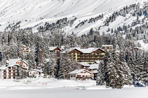 a ski resort covered in snow in front of a mountain at Hotel Waldhaus am See in Valbella