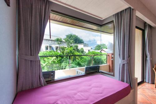 a bedroom with a pink bed and a large window at Karon Sea Sands Resort-SHA PLUS in Karon Beach