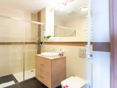 uma casa de banho com um lavatório, um chuveiro e um WC. em VacationClub – Olympic Park Apartament A503 em Kolobrzeg