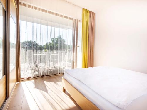 a bedroom with a bed and a large window at VacationClub – Baltic Park Plaża 22 Apartament 4.2.3. in Świnoujście