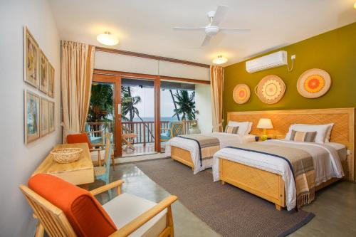 a hotel room with two beds and a balcony at Bay Villas Balapitiya in Balapitiya