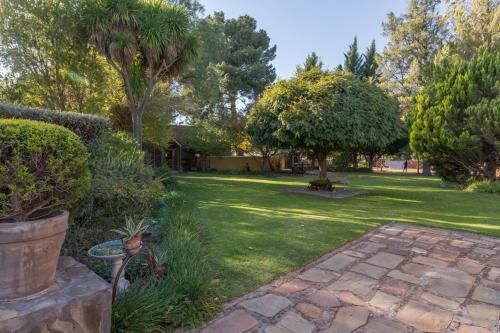 a garden with a lawn with trees and a brick path at GaMamadi Guest Farm in Nelspoort