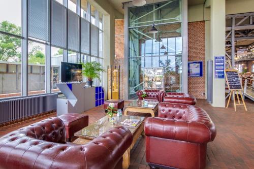 a lobby with leather couches and a television at Hotel Dömitzer Hafen in Dömitz