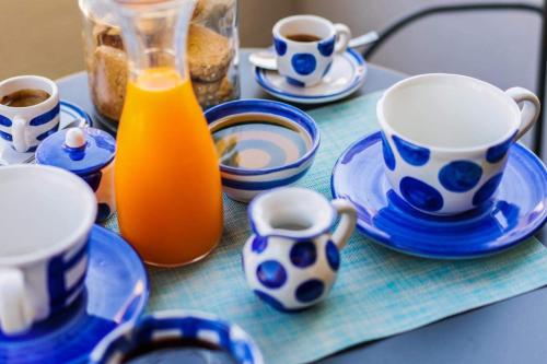 a table with blue and white cups and plates and orange juice at Smiling Apartments Vico Equense in Vico Equense