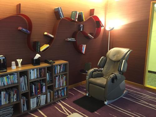 a library with a chair and a book shelf at Shanghai Centre Serviced Apartment in Shanghai