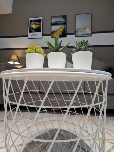 a white coffee table with four potted plants on it at Almas Suites Studio Seaview Netflix By STAY in Nusajaya