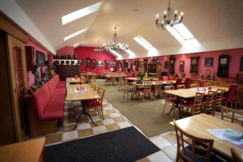 a restaurant with tables and chairs and red walls at Penzion Tři Koruny - budova Valerie in Havraníky