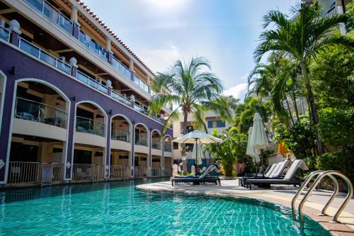 a swimming pool in front of a building with palm trees at Karon Sea Sands Resort-SHA PLUS in Karon Beach