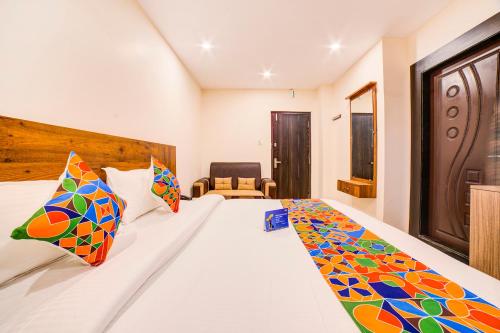 a bedroom with a large white bed with colorful pillows at FabHotel Spark Inn Dwarakanagar in Vijayawāda