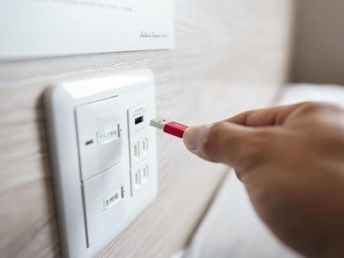 a person holding a cigarette in front of a lightswitch at Super Hotel Premier Akihabara in Tokyo